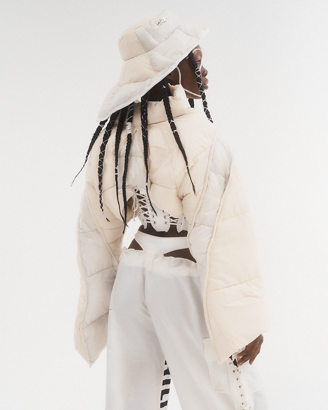 White puffer buckethat, cropped puffer coat, white baggy trousers with thong