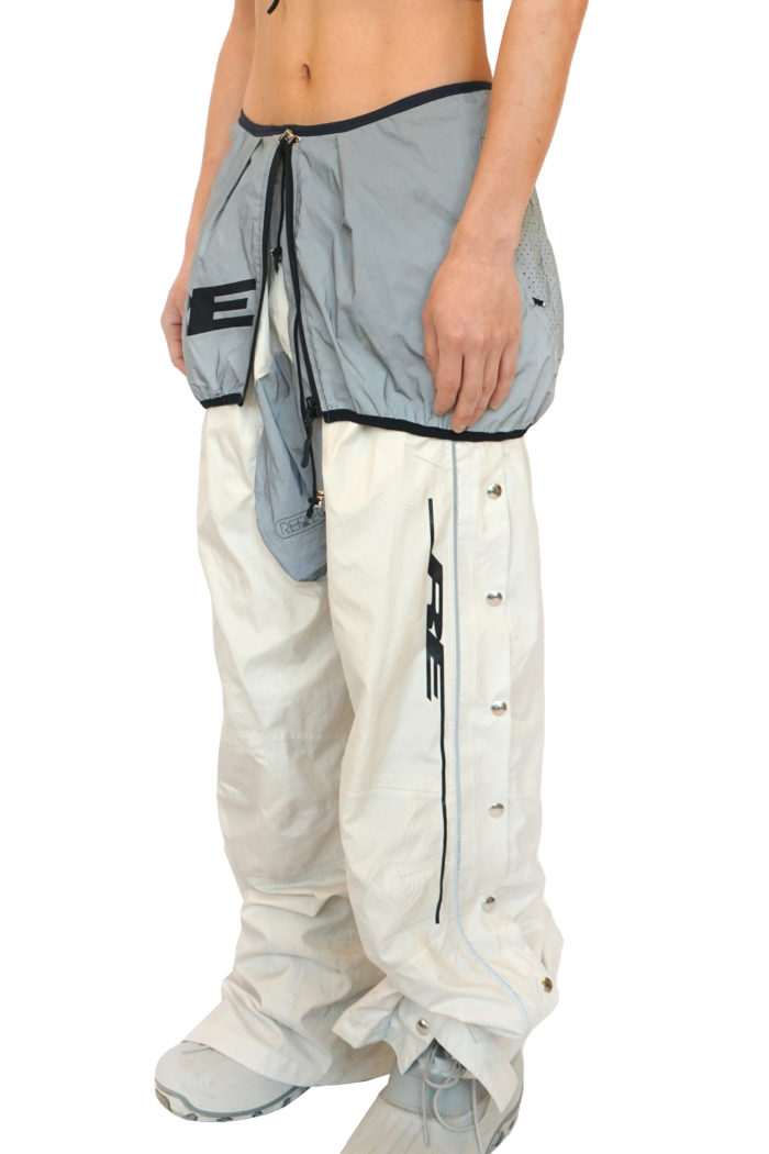 Reconstruct Track Pants, with push buttons, button down track pants in cream color. One of one, unique piece. With reflective detail and extra reflective layer, multi-wearable. Black Re logo, upcycled pants.