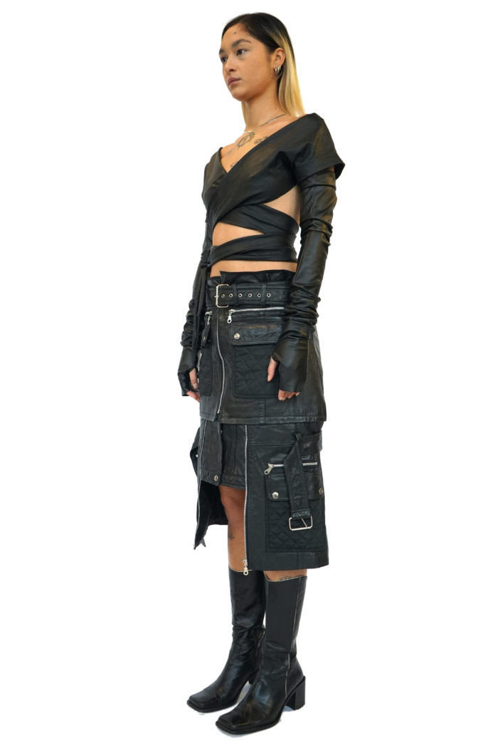 Reconstructed leather skirt, with zippers, pockets and belts, over the knee.